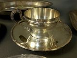 a silver cup and saucer sitting on a table