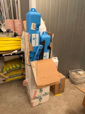 une pile de cartons et un bidon d'eau bleu posés par terre