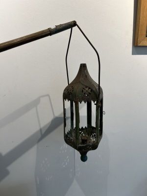 une lanterne à l'ancienne accrochée au mur, à côté d'un tableau