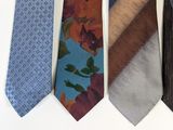 four different colored ties are lined up against a white wall