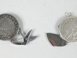 two coins and a knife on a white surface