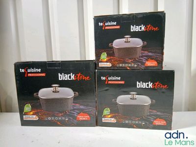 trois boîtes contenant des casseroles en pierre noire posées sur une table