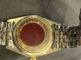 someone is holding a watch with a red dial on it