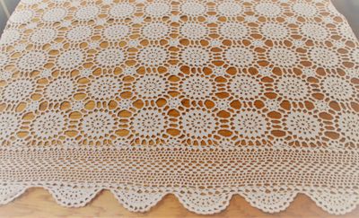 a close up of a crocheted table cloth on a wooden table