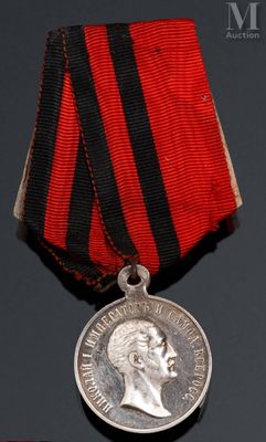 une vieille médaille ornée d'un ruban rouge et d'une médaille en argent posée sur un fond noir
