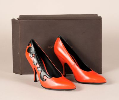 une paire de chaussures à talons hauts orange et noires posées devant une boîte