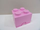 une brique Lego rose posée sur une table blanche