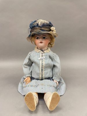 une image représentant une poupée assise par terre, vêtue d'une robe bleue et d'un chapeau