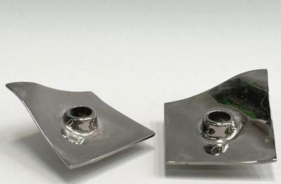 two pieces of silver metal on a white surface