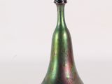 un vase en verre vert avec un couvercle noir posé sur une surface blanche