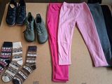 several pairs of shoes, socks, and leggings are laid out on a cardboard box