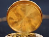 a gold pocket watch sitting on a black surface