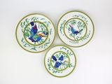 three plates with birds painted on them sitting on a white surface