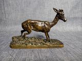 statue en bronze représentant un cerf sur un socle, sur fond gris