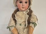 an antique doll with a bonnet and dress sitting on a white surface