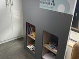 une bibliothèque avec des livres au milieu d'une pièce où se trouvent un canapé et un fauteuil