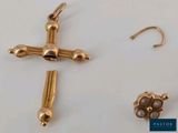 a gold cross and a pair of earrings on a table