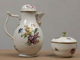 une théière blanche et une petite tasse posées sur une table
