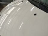 a white car that has a hole in the hood