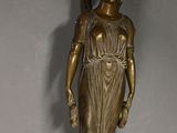 bronze statue of a woman holding a bird on a wall