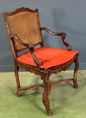 une vieille chaise en bois avec un coussin rouge posée sur un tapis vert
