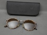 des lunettes de soleil et leur étui posés sur une table à côté d'une paire de lunettes