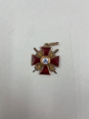 une croix rouge et dorée ornée d'un diamant
