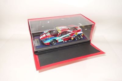 une petite voiture dans une vitrine posée sur une surface blanche