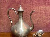 une théière en argent et une théière en argent posées sur une table en bois