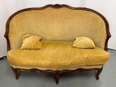 a yellow couch with two pillows on it in a room