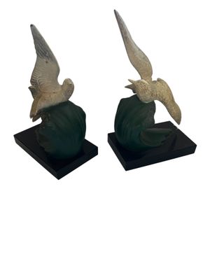 two statues of birds sitting on top of a black base