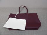 purple and white handbag with a tag attached to it on a gray surface