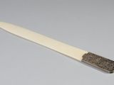 un couteau avec un manche posé sur une surface blanche
