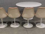 four chairs and a table in a room with a wall in the background