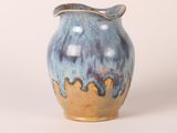 un vase bleu et jaune posé sur une surface blanche