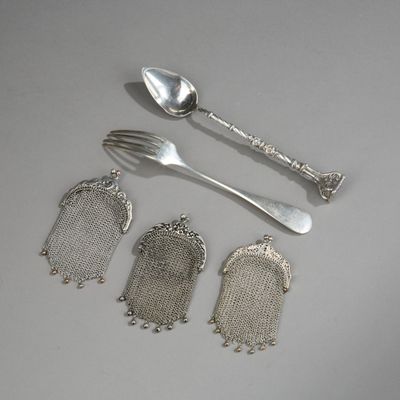 quatre cuillères en argent, une fourchette et un repose-cuillère posés sur une table