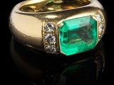 une bague en émeraude et diamant sur une surface noire