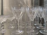 many wine glasses that are on a glass shelf