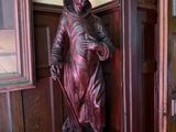 une statue représentant un homme tenant une canne dans une pièce