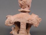 a clay sculpture of a woman on a rock