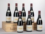 six bouteilles de vin rouge sont posées devant une caisse en bois