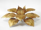 brass plated flower with leaves on a stand on a white surface