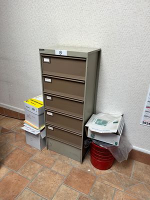 un classeur dans un coin de la pièce, à côté d'une poubelle