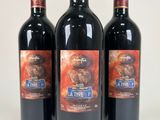 three bottles of red wine sitting next to each other on a white surface