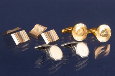 trois paires de boutons de manchette en or et une paire de boutons de manchette en argent sur un fond bleu