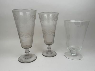 trois verres à pied et un verre à vin posés sur une surface blanche