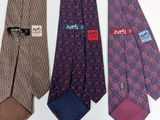 three different colored ties with different designs on them on a white surface