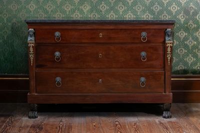 une commode dans une pièce au papier peint vert
