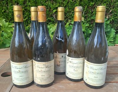six bottles of wine are lined up on a wooden table