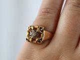 a woman ' s hand holding a ring with a diamond on it